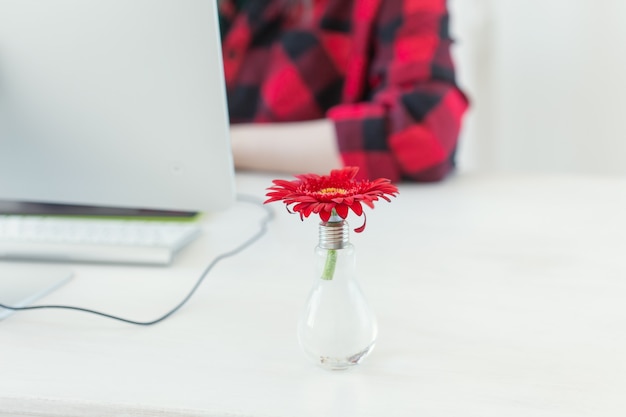 Local de trabalho com flor gerbera e computador. Escritório em casa minimalista com designer ao fundo