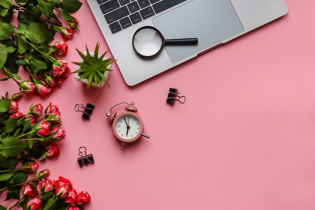 Local de trabalho com flores de despertador para laptop e lupa rosa