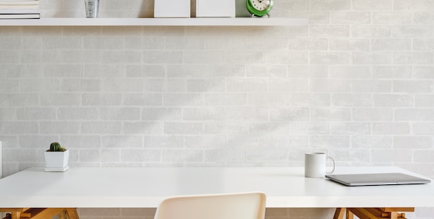 local de trabalho confortável com escrúpulos de escritório na mesa de madeira e parede de tijolo branco