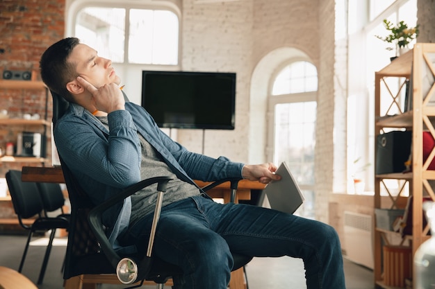 Local de trabalho criativo - espaço de trabalho organizado como você gosta para se inspirar. Homem trabalhando no escritório em traje confortável, posição relaxada e mesa bagunçada. Escolha a atmosfera desejada - ideal clara ou caótica.