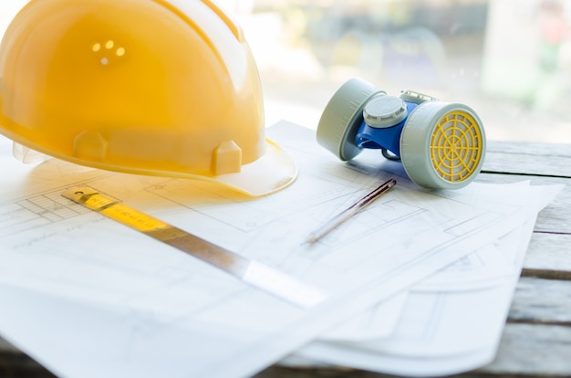 Local de trabalho de engenharia, desenhos, capacete protetor de construção e máscara contra poeira na área de trabalho