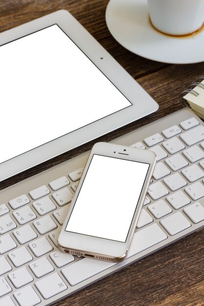 Local de trabalho de escritório. telefone e tablet na tela em branco, com teclado e xícara de café
