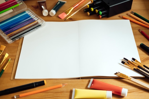 Local de trabalho de maquete de artista criativo em mesa de madeira plana com vista superior com caderno em branco com