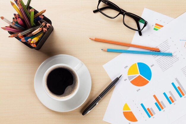 Local de trabalho de mesa de escritório com xícara de café e gráficos