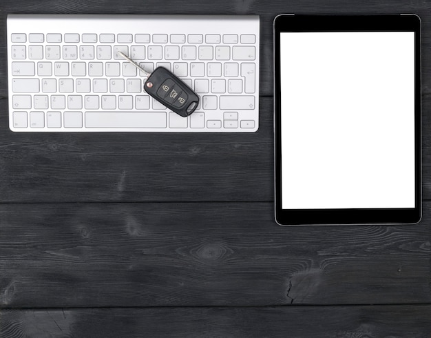 Foto local de trabalho de negócios com teclado sem fio, computador tablet e as chaves do carro em fundo preto de madeira. mesa de escritório com espaço de cópia. espaço vazio para texto