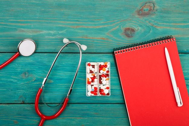 Local de trabalho de um médico Estetoscópio vermelho e comprimidos na mesa de madeira azul