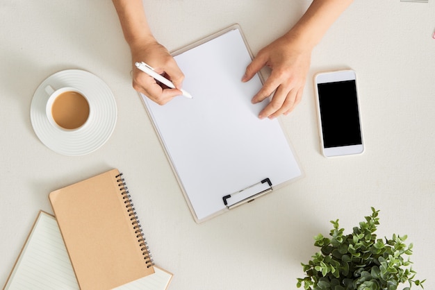 Local de trabalho do escritor, reescritor. Feminino mão segurando a caneta e escrevendo no bloco de notas. Conceito de planejamento de negócios e brainstorming