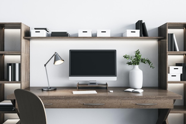 Local de trabalho doméstico de madeira estilo eco com monitor de computador moderno com lâmpada de aço de vaso branco de tela preta em branco e parede branca em maquete de fundo