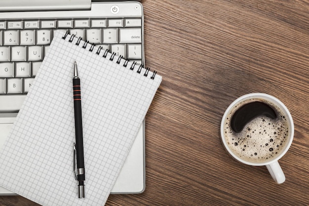 Local de trabalho moderno com laptop, caderno, caneta e xícara de café