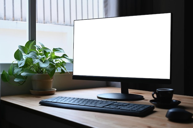 Local de trabalho simples com xícara de café computador pc e planta em vaso na mesa de madeira