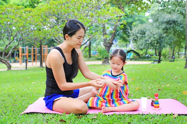 Loção appying do corpo da mãe para a filha no parque do verão.