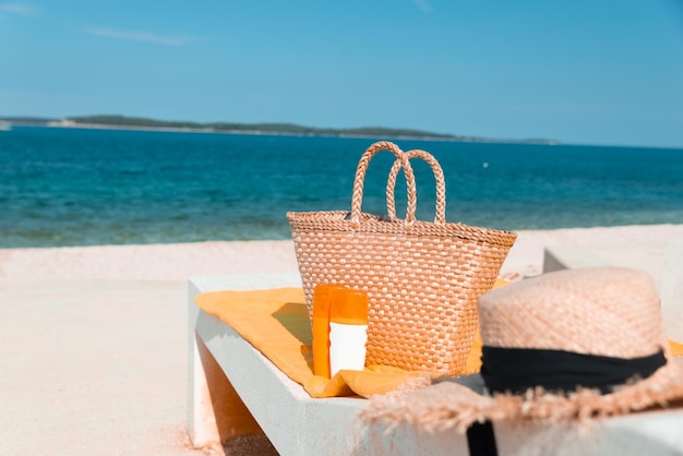 Loção creme de proteção solar na espreguiçadeira com bolsa de palha e chapéu de férias de verão