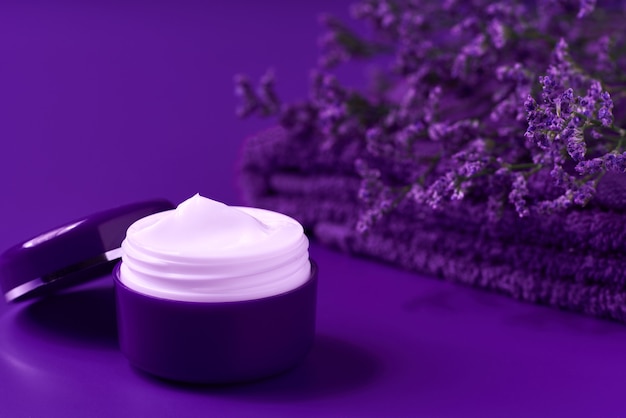 Loção hidratante de luxo ou creme corporal em um frasco roxo sobre uma mesa, copie o espaço para texto.