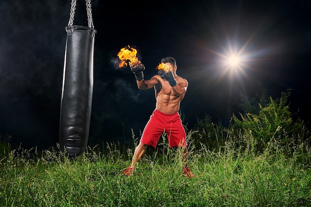 Locher Sandsack des Berufsboxers mit brennenden Handschuhen