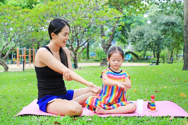 Loción corporal para la hija de la madre en el parque de verano.