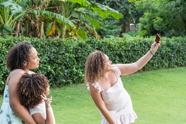 Lockige Mutter macht mit ihren Töchtern im Freien ein Selfie