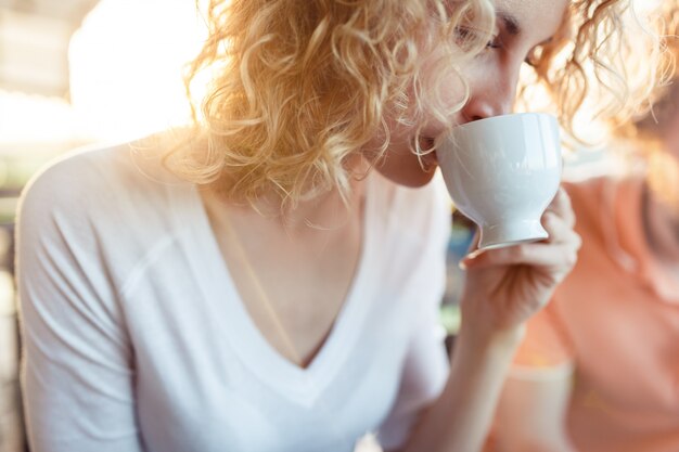 Lockiges Mädchen, das eine Tasse Kaffee hält