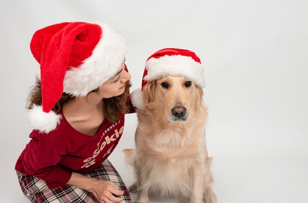 Lockiges Mädchen im Weihnachtsmannhut mit Hundelabrador