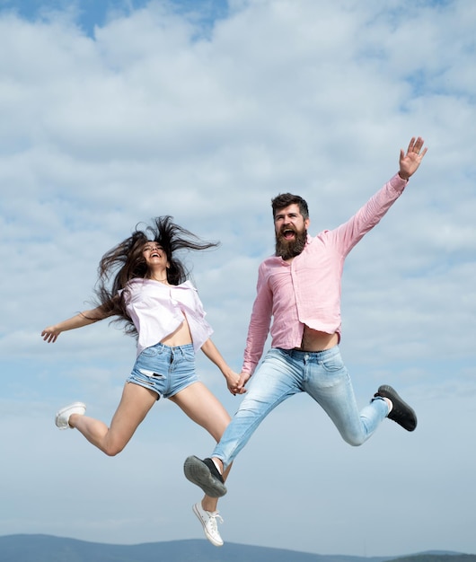 Foto loco enamorado, la mujer y el hombre saltan en el cielo nublado disfrutan de un tiempo sin preocupaciones juntos, las vacaciones de verano se sienten ...