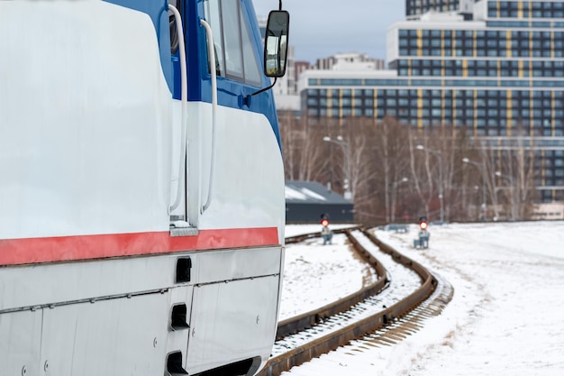 Locomotiva moderna em uma ferrovia de bitola estreita contra o pano de fundo da cidade