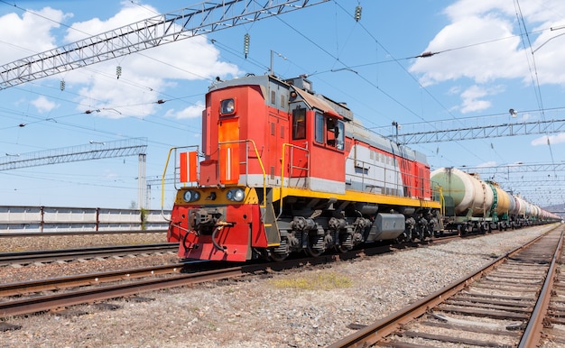 Locomotora de carga tira de tren con tanques de combustible contra el cielo azul.