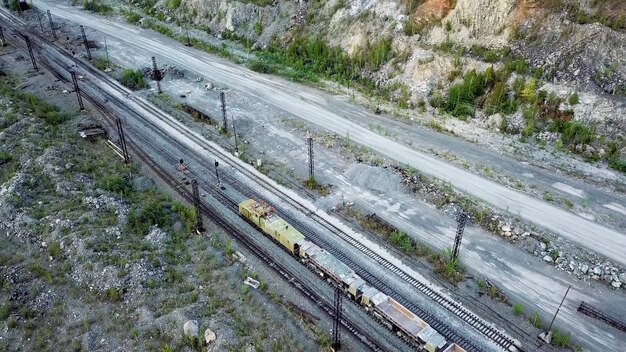 La locomotora diesel está empujando un vagón lleno de escombros de piedra en el fondo de una cantera para