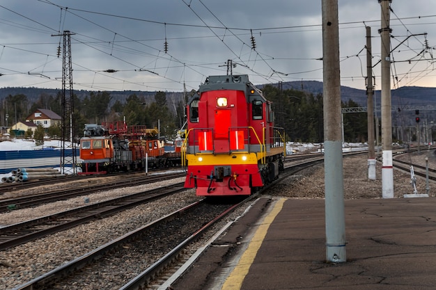 Una locomotora diesel se mueve sobre rieles en una estación de trenes suburbanos