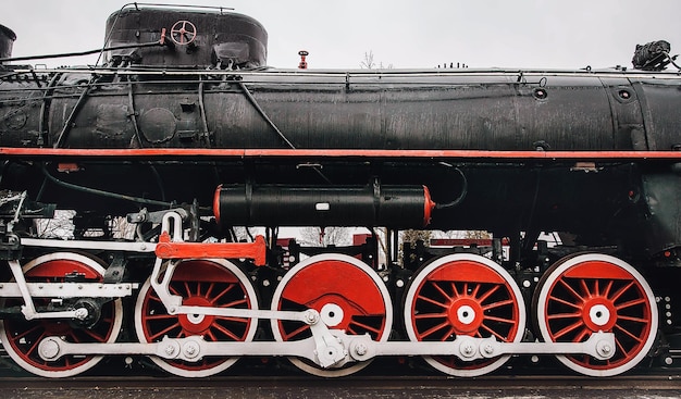 Foto locomotora de vapor antigua sobre grandes ruedas rojas las ruedas del tren cierran el ferrocarril