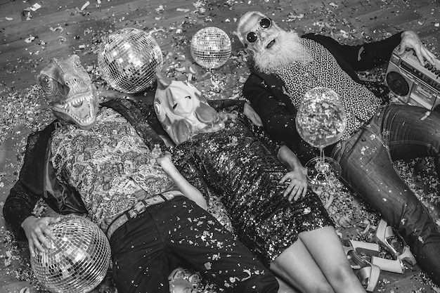 Locos celebrando la fiesta de carnaval dentro de la discoteca Centrándose en la máscara de pollo Edición en blanco y negro