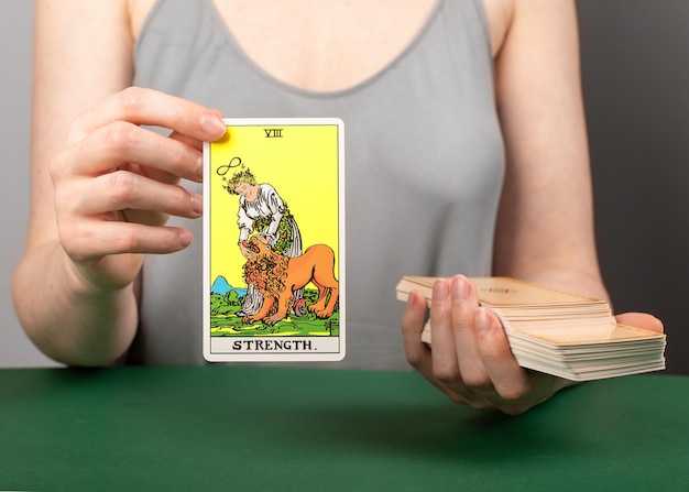 Lodz Polonia 15 de abril de 2023 Fuerza arcana mano sosteniendo mostrando la carta del tarot durante la adivinación