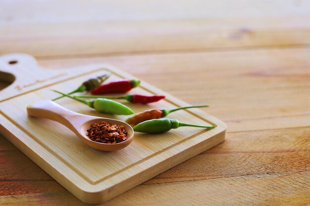 Löffel Cayennepfeffer und frische Chilis auf Holz