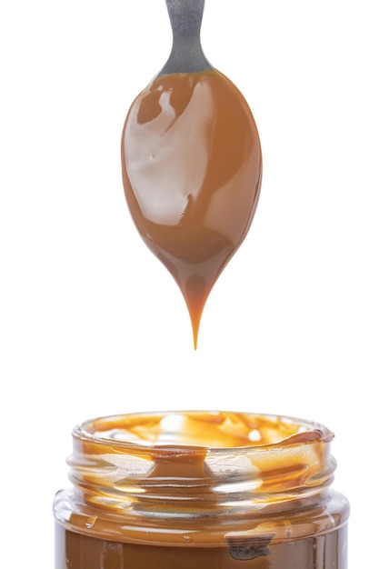 Löffel, der Dulce de Leche aus einem Glas traditioneller Süßigkeit aus Argentinien schöpft