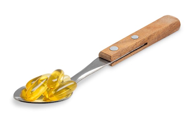 Löffel mit Haufen gelber Omega-3-Fettsäurekapseln oder Fischöl-Nahrungsergänzungsmittel auf Weiß