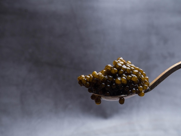 Löffel mit köstlichem schwarzem Kaviar auf grauem Hintergrund
