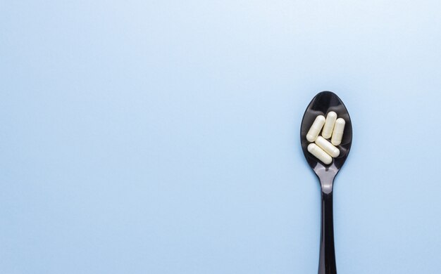 Löffel mit Pillen auf einem blauen Tisch. Medizin. Medikament. Gesundheit.