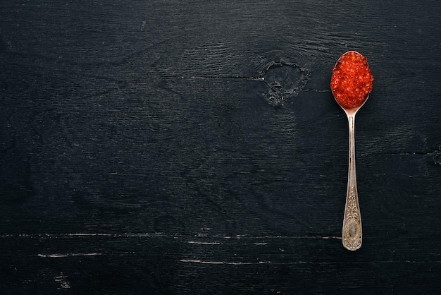 Löffel mit rotem Kaviar auf einem hölzernen Hintergrund Draufsicht Freier Platz für Text