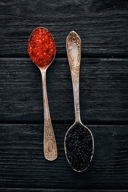 Löffel mit schwarzem und rotem Kaviar auf Holzhintergrund Draufsicht Freier Platz für Text