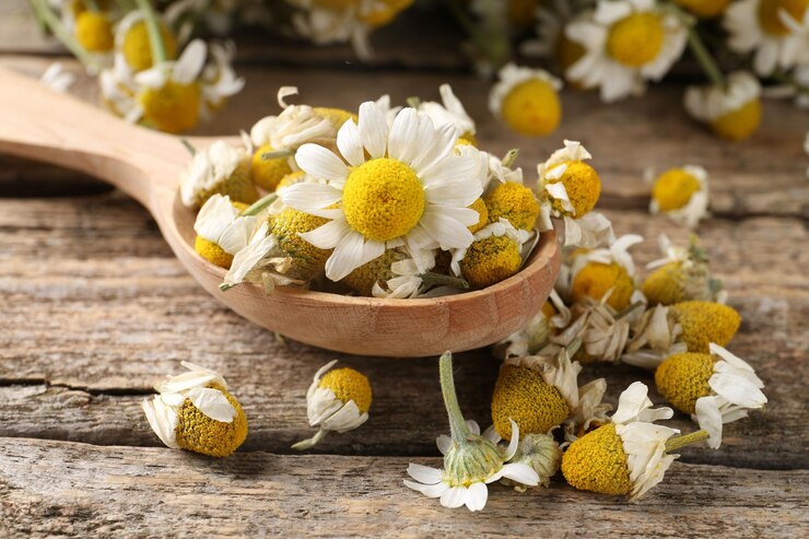 Foto löffel mit trockenen und frischen kamillblumen auf einem holztisch in nahaufnahme