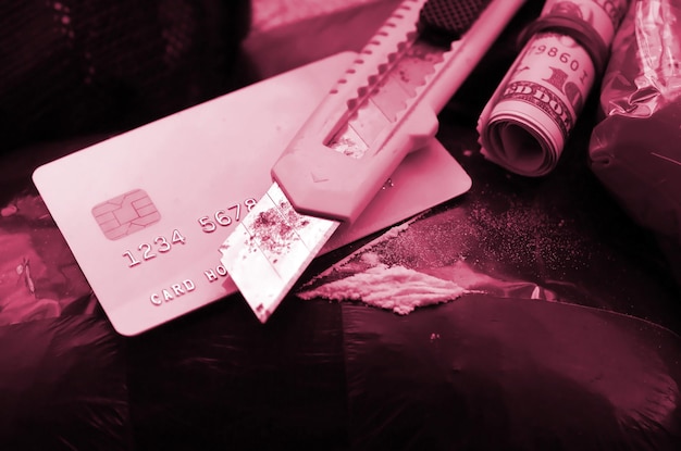 Löffel voller Heroin und Papiermesser liegen auf Drogenpackungen und Kreditkarte mit Dollar-Rollbildton