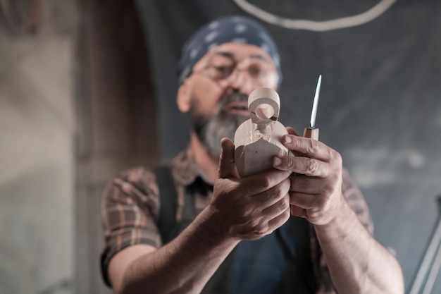 Löffelhandwerksmeister in seiner Werkstatt mit handgefertigten Holzprodukten und Werkzeugen, die Kurve und Linie gerade prüfen. Foto in hoher Qualität