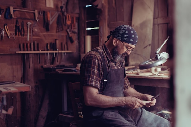 Löffelmeister in seiner Werkstatt mit Holzprodukten und Werkzeugen. Foto in hoher Qualität