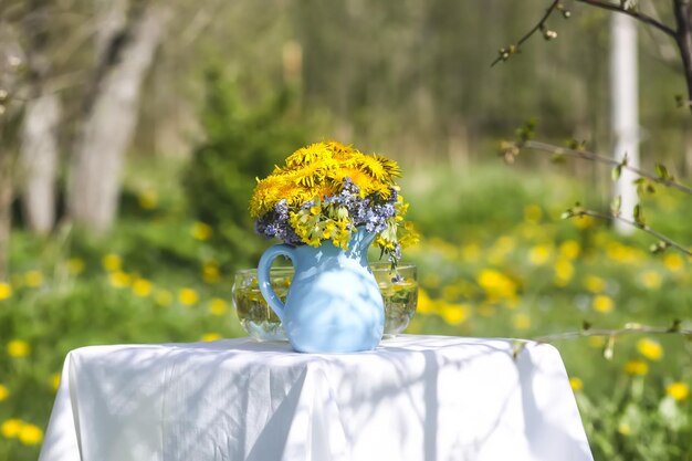 Löwenzahnblumen im blauen Keramikkrug im Sonnenlicht Florale Komposition im Freien