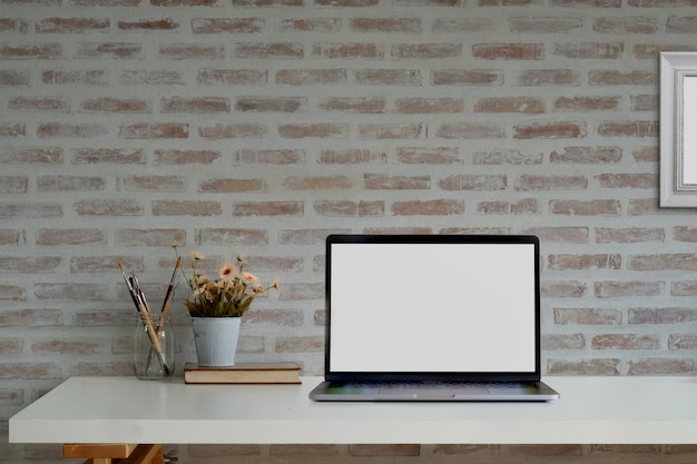 Loft espaço de trabalho com laptop de tela em branco de maquete e suprimentos.
