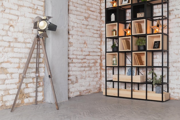 Loft moderno interior de estudio fotográfico de sala de estar, lámpara de fuente, estantería de biblioteca detrás de una pared de ladrillo vintage natural. Concepto de espacio comercial de obras de arte. lámpara fuente. Espacio de copia de foto de maqueta de fondo.