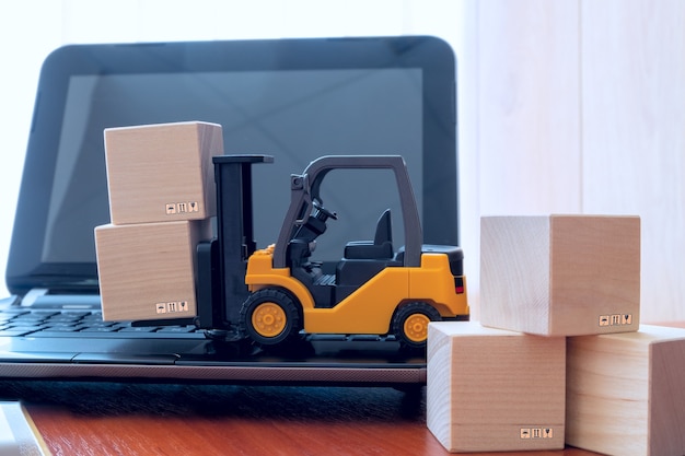 Logística, suministro, concepto de compra en línea: la carretilla elevadora mueve el cubo en el teclado.