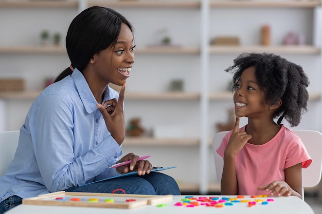 Logopeda afroamericana trabajando con una niña en la clínica