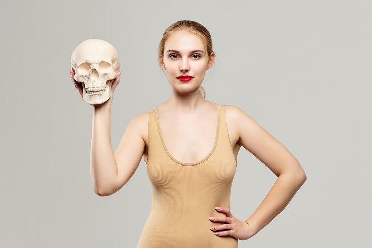 Foto loira atraente tem uma caveira nas mãos. o conceito de fotografia é adequado no campo da cosmologia, medicina e saúde.
