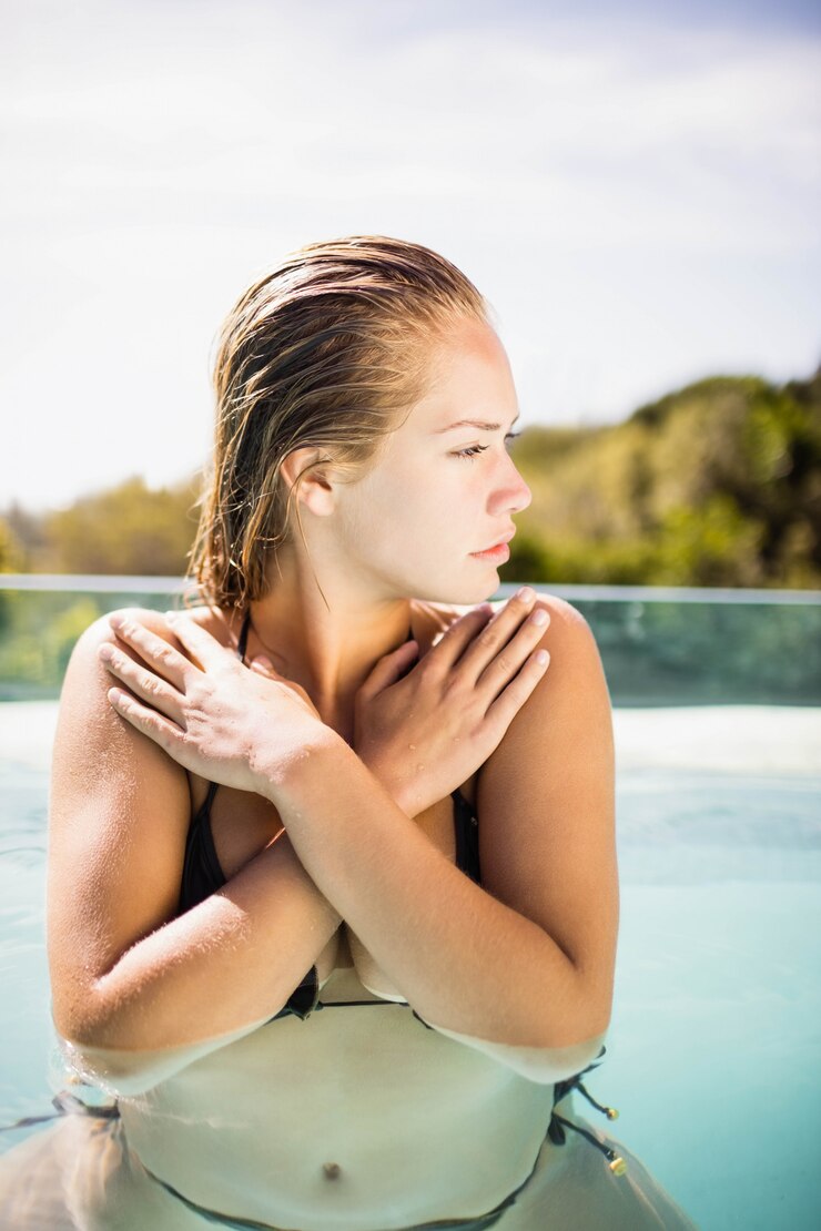 Foto loira carrancuda na piscina cruzando os braços
