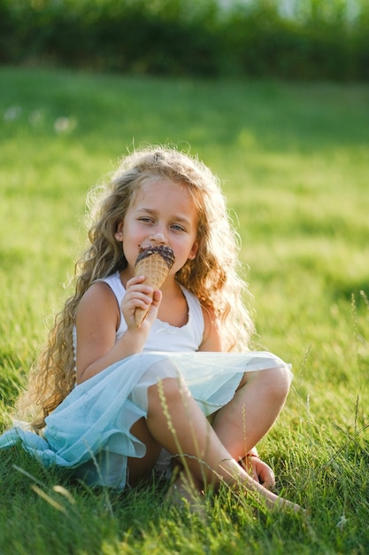 Loira com cabelo comprido se diverte comendo sorvete em um parque de verão.