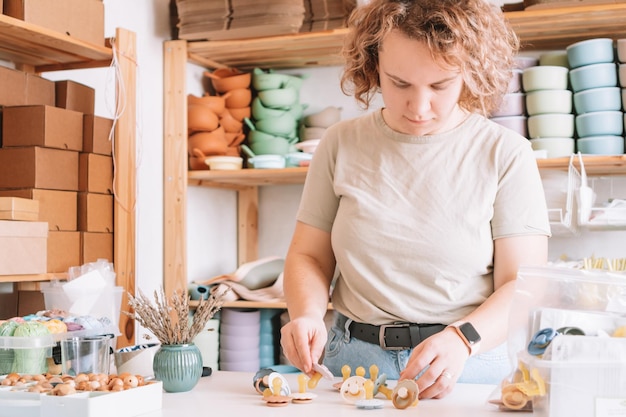 Loira confiante mulher encaracolada fazendo e projetando chupetas de silicone artesanais para bebês recém-nascidos acessórios ecológicos naturais